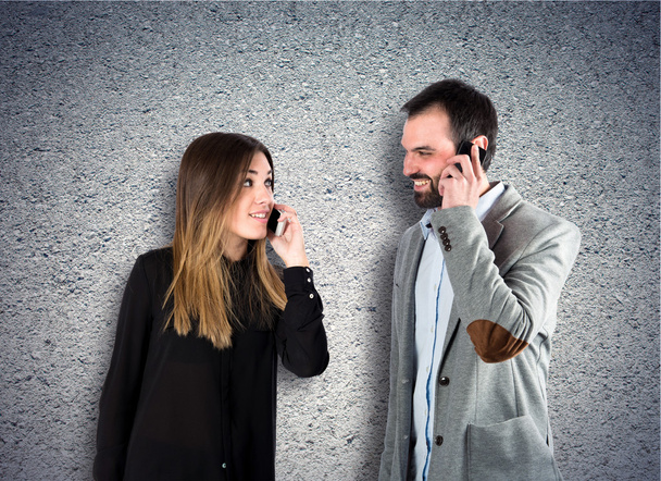Couple talking to mobile  over textured background  - 写真・画像