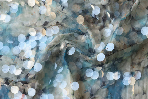 Top view of cloth with shiny silver sequins abstract background. Stylish wavy fabric texture backdrop - 写真・画像