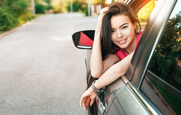 Beautiful young asian woman looks out of the car window. Road trip background with copy space. - Zdjęcie, obraz