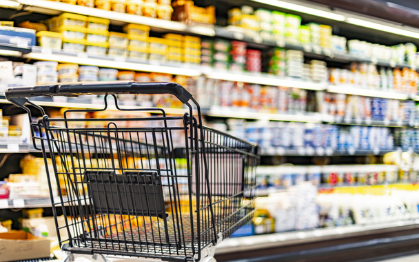 A shopping cart by a store shelf in a supermarket - Φωτογραφία, εικόνα