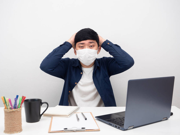Homem usando máscara sentado no local de trabalho sentir dor de cabeça sobre o trabalho - Foto, Imagem