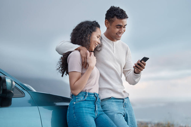 Fotografía de una joven pareja usando un teléfono en un viaje por carretera juntos. - Foto, imagen