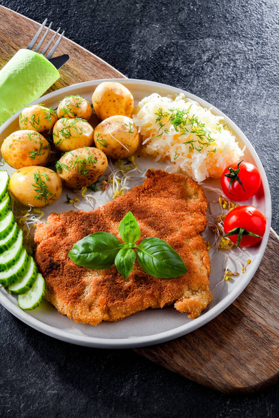 Pork breaded cutlet coated with breadcrumbs served with potatoes and cabbage - Foto, imagen