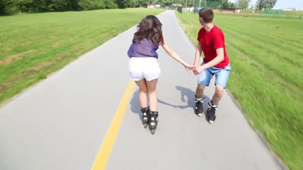 Young woman and man rollerblading and performing in park on a beautiful warm day, doing tricks - Video