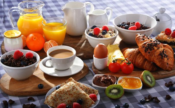 Snídaně podávaná s kávou, pomerančovým džusem, croissanty, palačinkami, vejci, cereáliemi a ovocem. - Fotografie, Obrázek