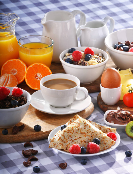 Frühstück mit Kaffee, Orangensaft, Croissants, Pfannkuchen, Ei, Müsli und Obst. - Foto, Bild