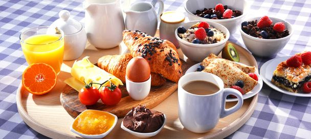 Breakfast served with coffee, orange juice, croissants, pancake, egg, cereals and fruits. - Photo, Image
