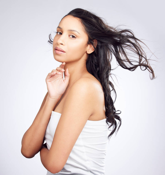 Фото молодой женщины, позирующей на белом фоне со здоровыми волосами. - Фото, изображение