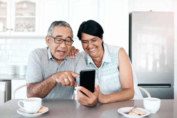 Fotografía de una pareja de ancianos usando un teléfono en casa. - Foto, imagen