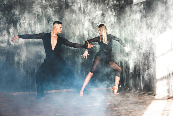 Un par de bailarines de salón profesionales bailan en el estudio loft. Hermosa actuación artística. Concepto de vida deportiva. Pasión y danza emocional. - Foto, Imagen