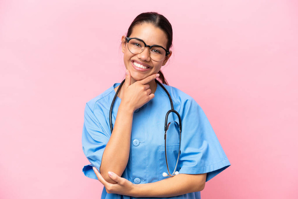 Young nurse Colombian woman isolated on pink background smiling - Foto, afbeelding