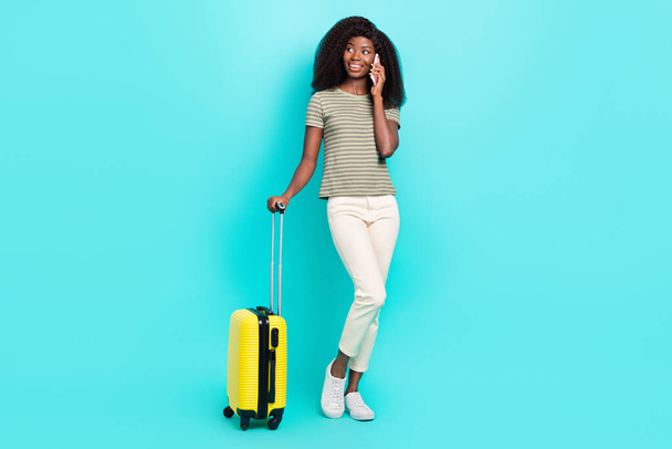 Full size portrait of charming person hold speak telephone suitcase isolated on bright cyan color background. - Foto, imagen