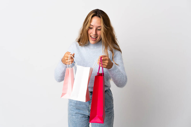 Junge blonde Frau isoliert auf weißem Hintergrund mit Einkaufstaschen und Blick hinein - Foto, Bild