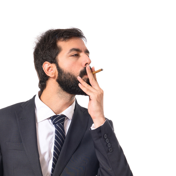 Businessman smoking over isolated white background - Foto, afbeelding