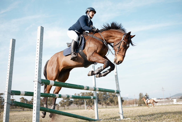 Повнометражний знімок молодої жінки-гонщиці, що стрибає через перешкоду на коні
. - Фото, зображення