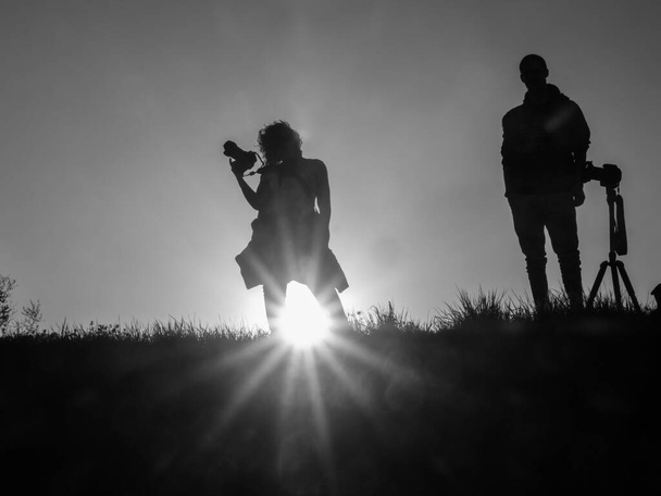 Silhouette of woman and man with photo camera during sunset time. Photographers. - Fotó, kép
