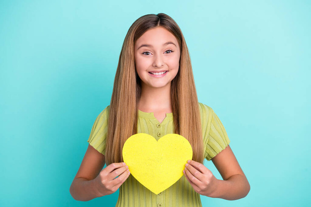 Portrait of cheerful nice girl hands hold paper heart symbol card beaming smile isolated on turquoise color background. - Foto, imagen