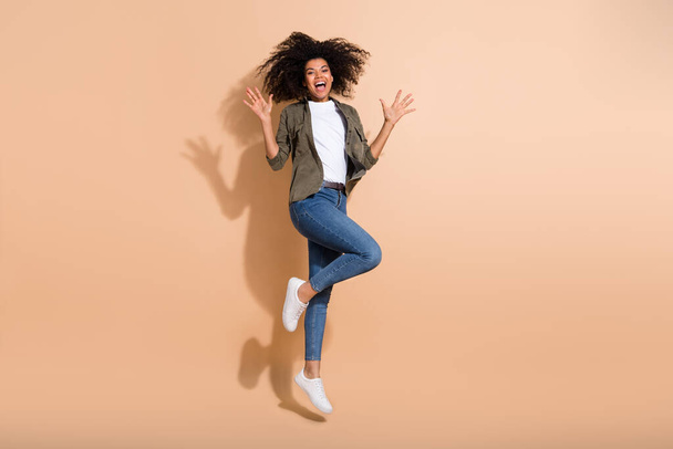 Full length body size view of attractive cheerful amazed girl jumping having fun isolated over beige pastel color background. - Foto, immagini