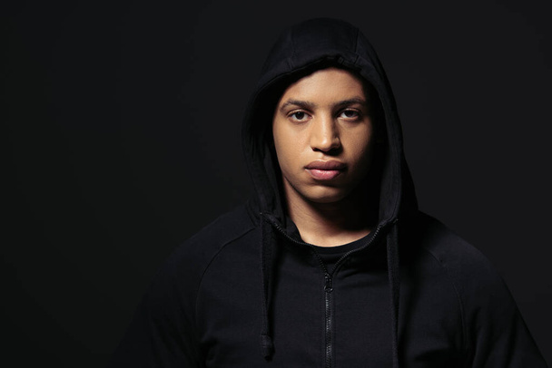 African american hooligan in hoodie looking at camera isolated on black  - Foto, immagini