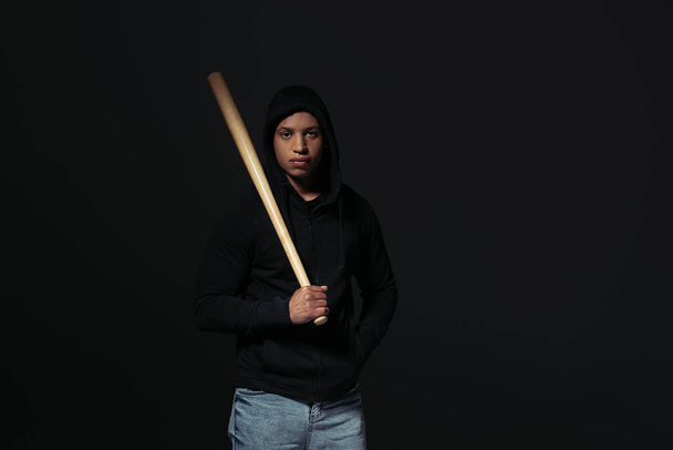 African american hooligan holding baseball bat isolated on black  - Фото, зображення