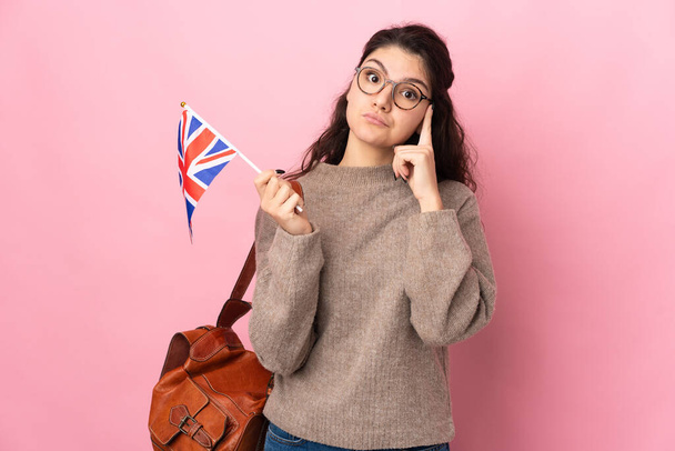 Jovem mulher russa segurando uma bandeira do Reino Unido isolado em fundo rosa pensando uma ideia - Foto, Imagem