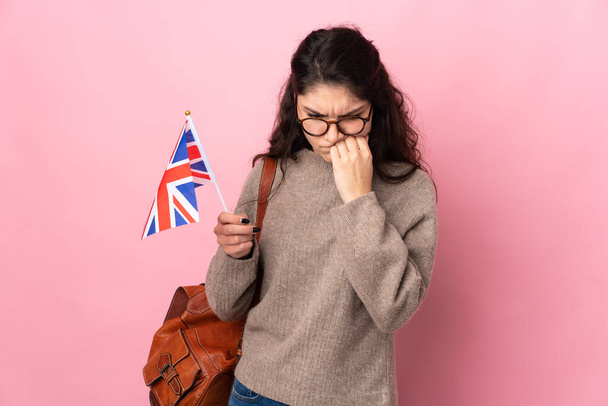 Young Russian woman holding an United Kingdom flag isolated on pink background having doubts - Photo, Image