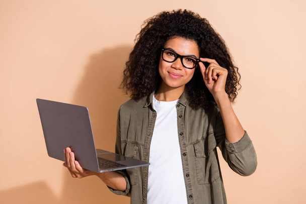Portrait of attractive cheerful skilled girl it specialist touching specs using laptop isolated over beige pastel color background. - Foto, Imagem