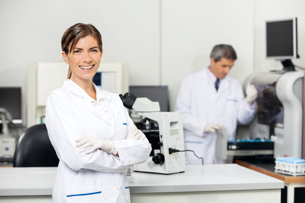 Hymyilevä naispuolinen tutkija laboratoriossa
 - Valokuva, kuva