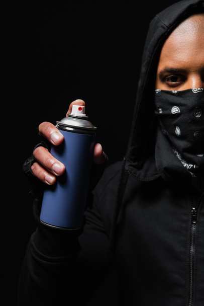 Cropped view of african american bandit with mask on face holding spray paint isolated on black  - Photo, Image