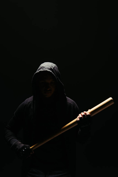 Silhouette of bandit in hoodie holding baseball bat isolated on black  - Fotó, kép
