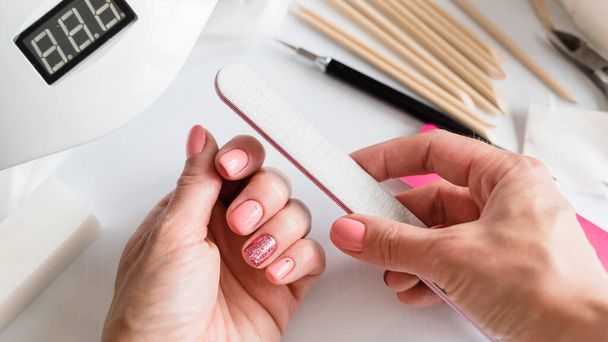 Nail manicure with a nail file brush. Woman beautiful nail care process. Manicure for yourself. Removing gel polish. Nail care. Close-up - Foto, Imagen