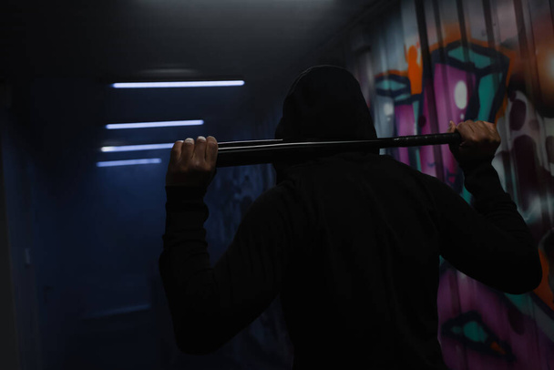 Back view of african american vandal in hoodie holding baseball bat in garage with graffiti  - Foto, immagini