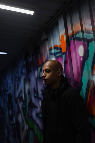 Африканський американський хуліган стоїть біля графіті в гаражі.  - Фото, зображення