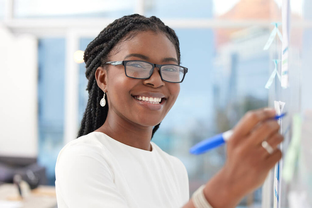 Fotografía de una joven empresaria tomando notas mientras hace una lluvia de ideas en una oficina. - Foto, imagen