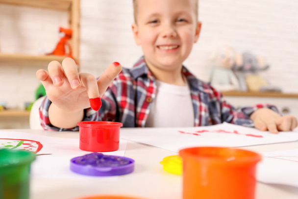 Little boy painting with finger at white table indoors, focus on hand - Foto, immagini