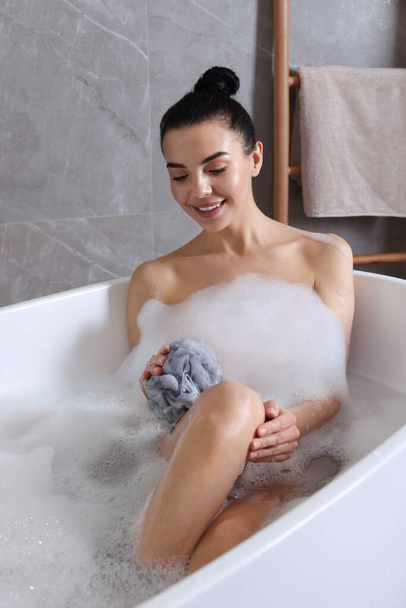Woman taking bath with mesh pouf indoors - Foto, Imagen