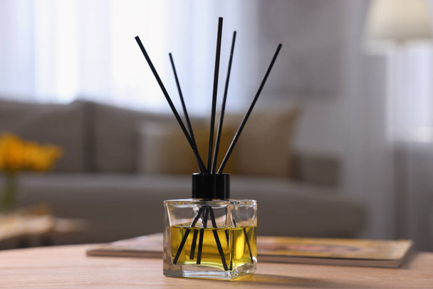 Reed diffuser on wooden table indoors. Cozy atmosphere - Zdjęcie, obraz