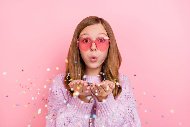 Photo of young lovely girl blow confetti event festive wear eyeglasses isolated over pink color background. - Фото, изображение