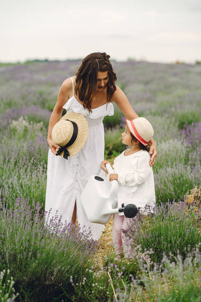 Mother with little daughter on lavender background. Beautiful woman and cute baby playing in meadow field. Family holiday in summer day. - Foto, Imagem