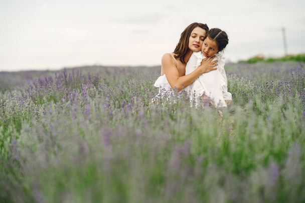 Mother with little daughter on lavender background. Beautiful woman and cute baby playing in meadow field. Family holiday in summer day. - Valokuva, kuva