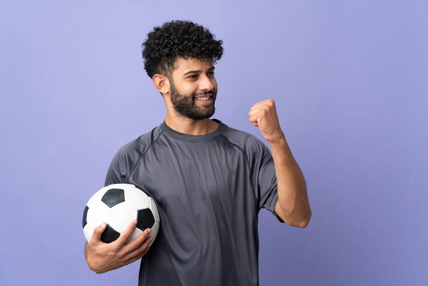 ハンサムなモロッコの若いサッカー選手男上の孤立した上に紫の背景にある勝利を祝う - 写真・画像