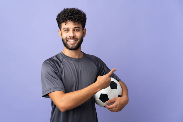 Handsome Moroccan young football player man over isolated on purple background pointing back - Photo, image