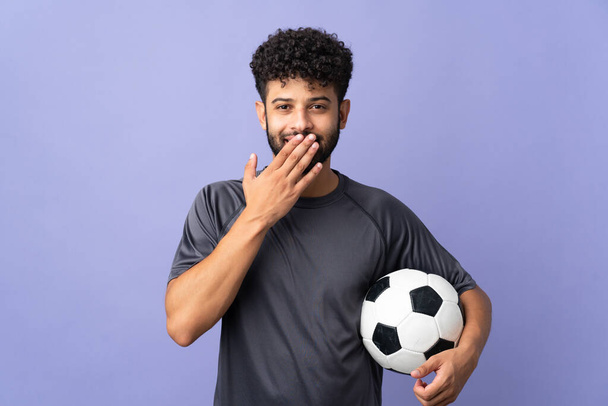 Handsome Moroccan young football player man over isolated on purple background happy and smiling covering mouth with hand - Fotografie, Obrázek