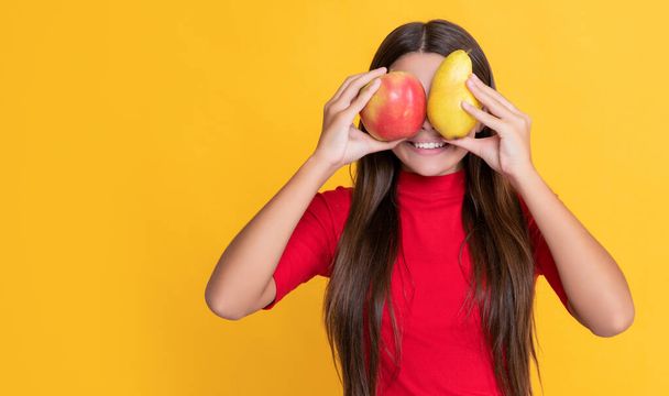 positive child with fresh apple and pear on yellow background. - Valokuva, kuva