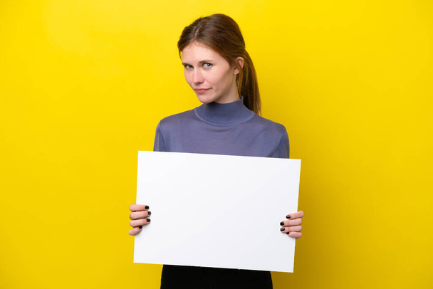 Young English woman isolated on yellow background holding an empty placard - Fotografie, Obrázek