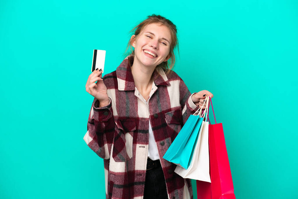 Jovem inglesa isolada em fundo azul segurando sacos de compras e um cartão de crédito - Foto, Imagem