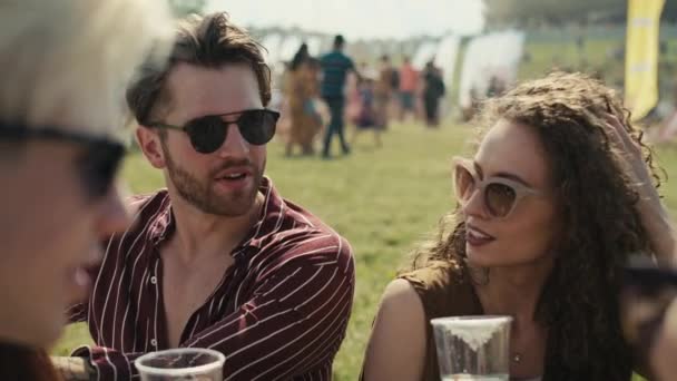 Група друзів сидить на траві разом на музичному фестивалі і п'є пиво під час спілкування. Знімок з гелієвою камерою RED у 8K
.  - Кадри, відео