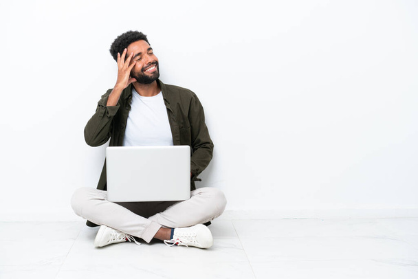 Young Brazilian man with a laptop sitting on the floor isolated on white has realized something and intending the solution - 写真・画像