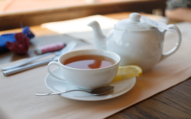 Kopje thee met citroen en theepot - Foto, afbeelding