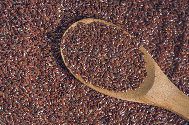 τους σπόρους λιναριού με ένα ξύλινο κουτάλι σε λινάτσα φόντο - Φωτογραφία, εικόνα